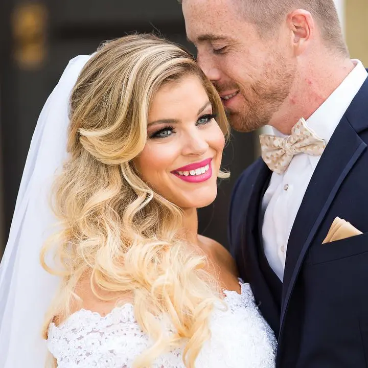 Newly married husband pressing his nose on the side of his bride's head.