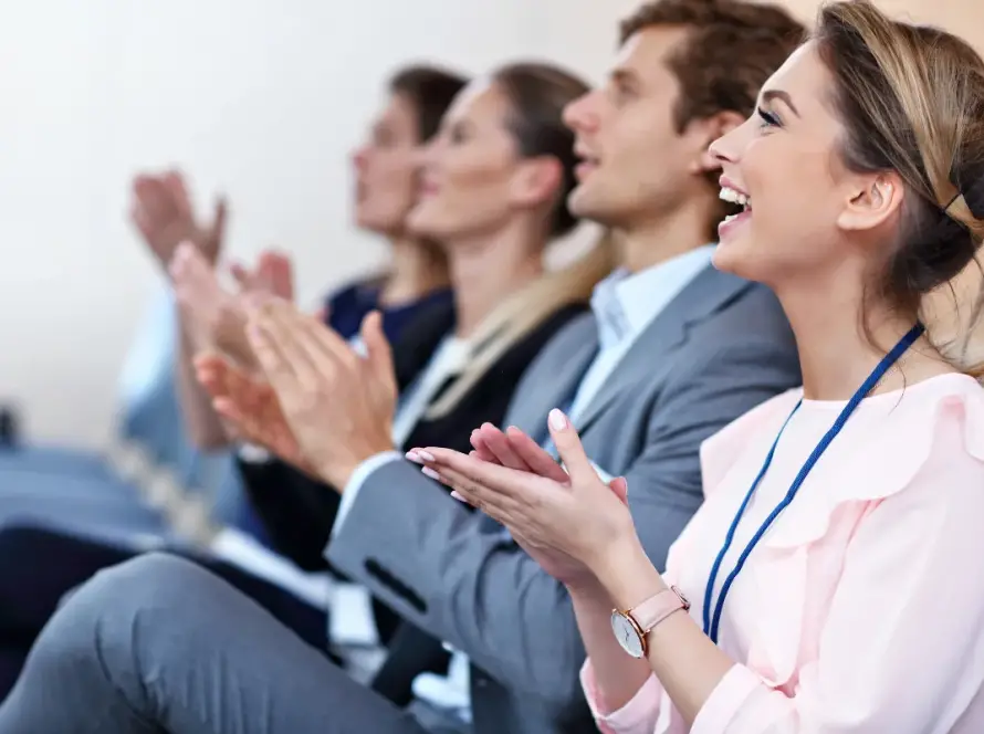 Attendees applauding at a corporate conference, smiling and engaged during a business presentation or seminar