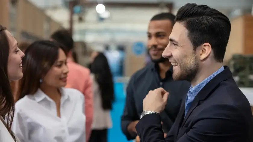Professionals engaging in conversation at a networking event, smiling and interacting in a business conference setting